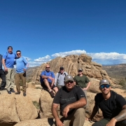 group of firefighters posed on a mountain with blue sky in background