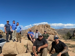 group of firefighters posed on a mountain with blue sky in background